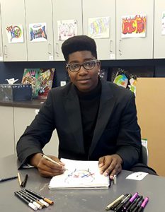 Photo of student sitting at a table drawing in a sketchbook.