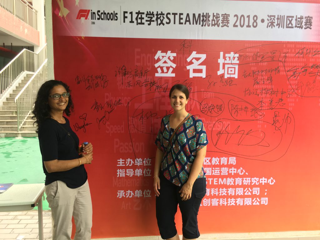 Photo of two teachers standing in front of a poster written in Chinese