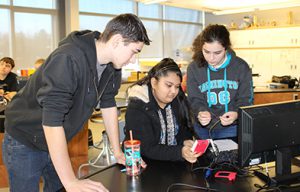 photo of students working together around a computer.