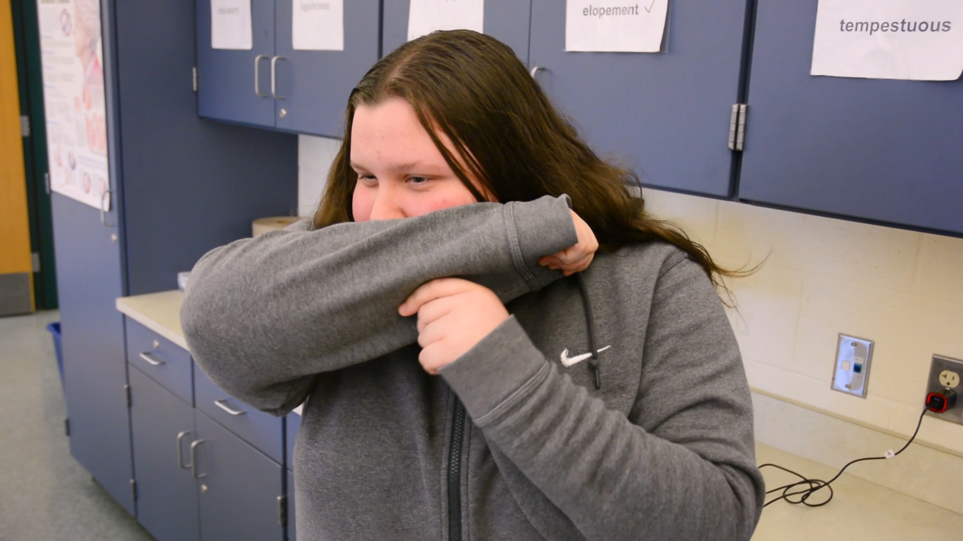 Photo of teenager coughing into elbow