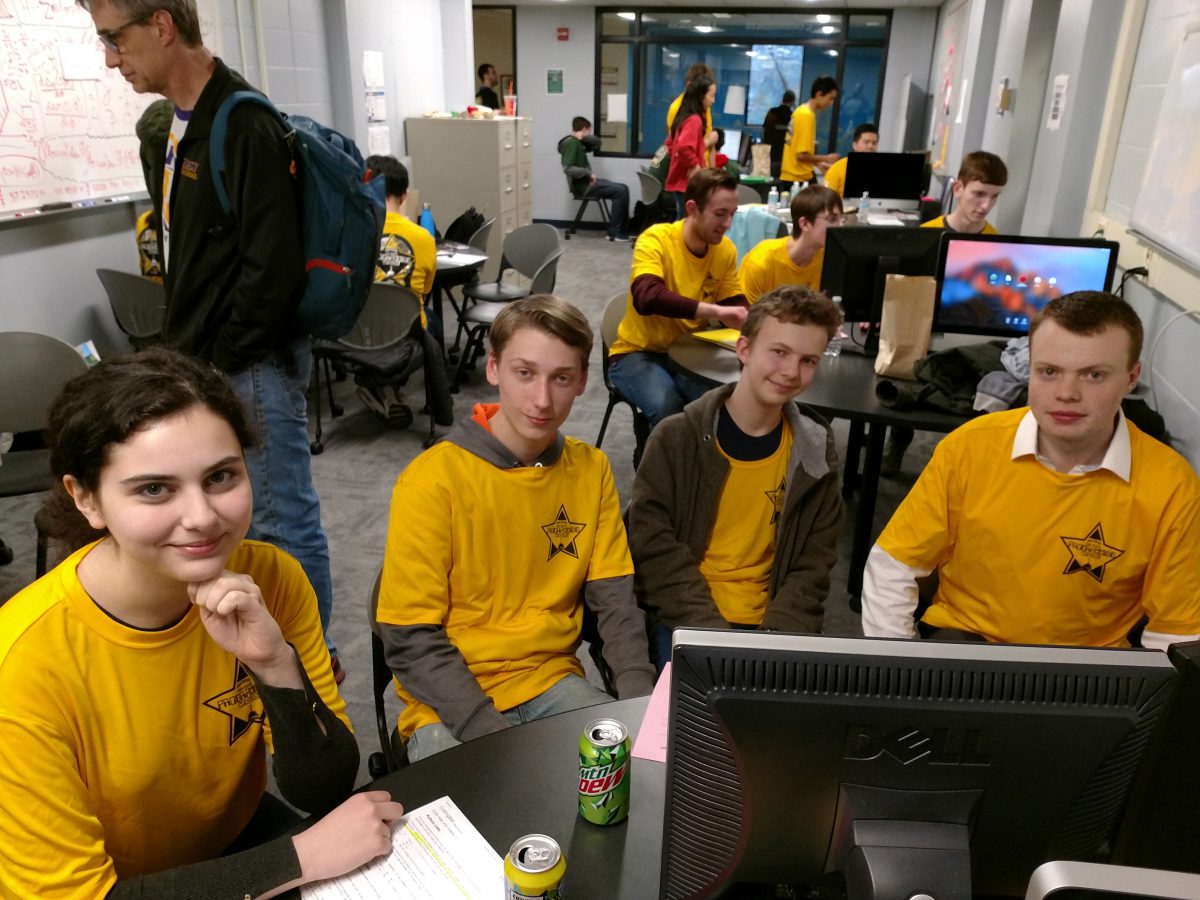 Group of students in gold shirts around a computer