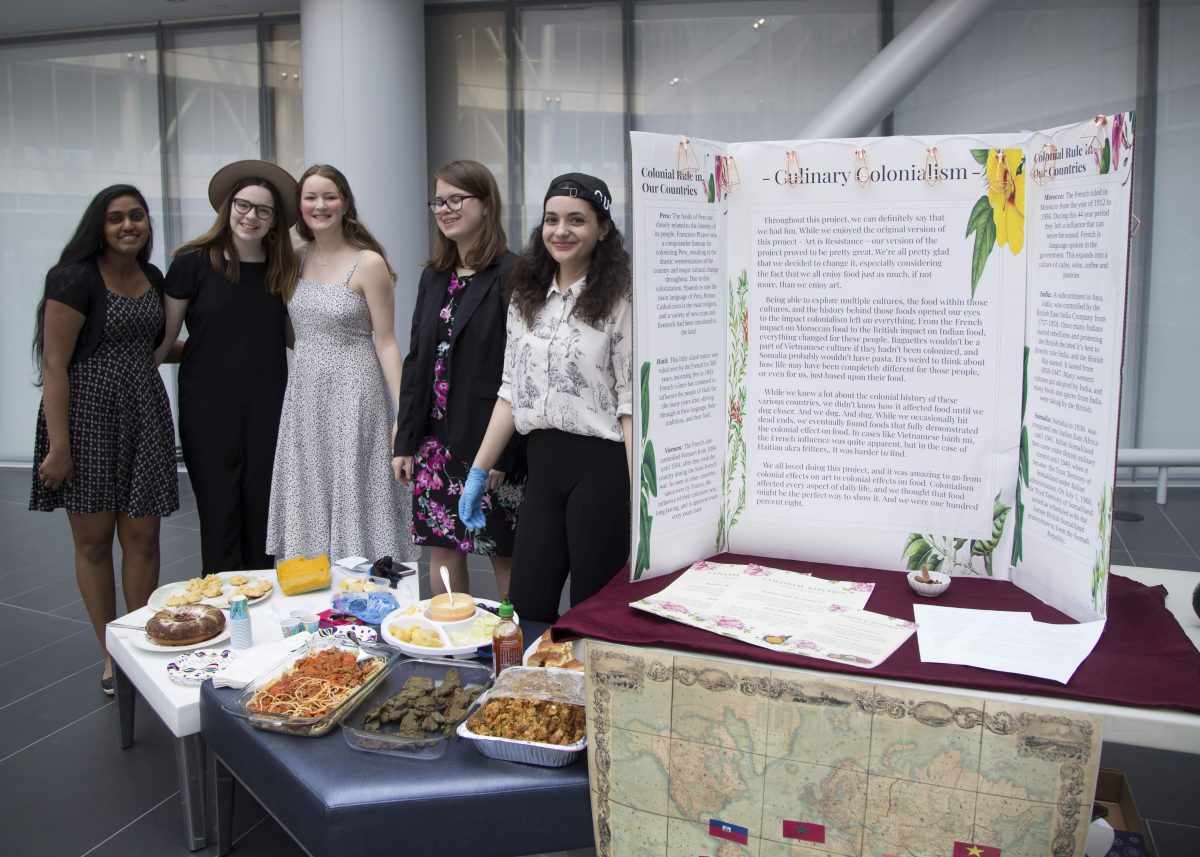 Photo of five students next to a tri-fold poster and table of food.