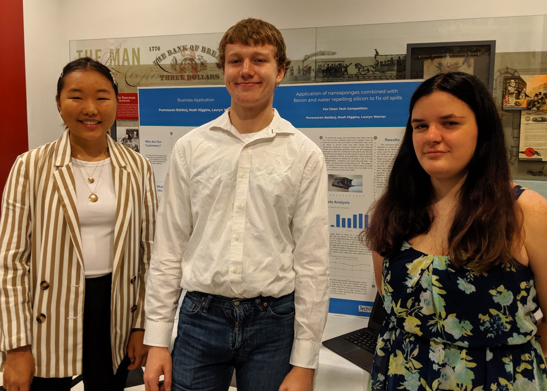 Photo of three students in front of a display board